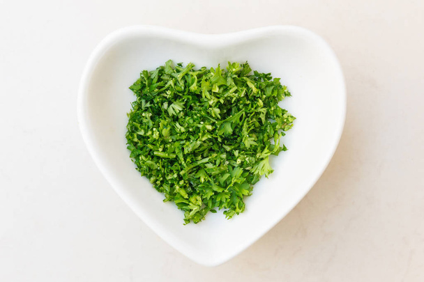 Chopped parsley in heart shaped bowl. - Photo, Image