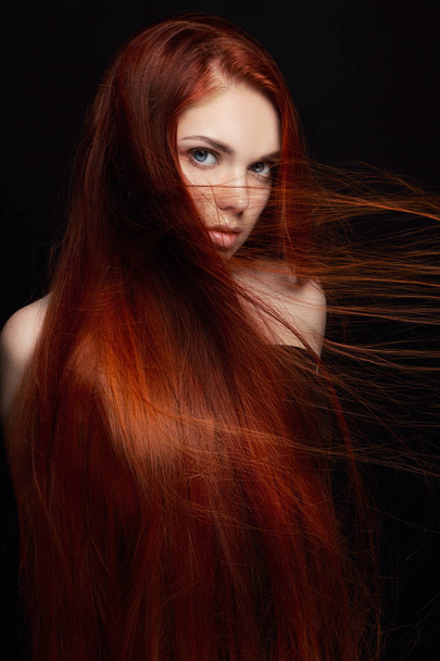 Sexy beautiful redhead girl with long hair. Perfect woman portrait on black background. Gorgeous hair and deep eyes. Natural beauty, clean skin, facial care and hair. Strong and thick hair. Flower - Photo, image