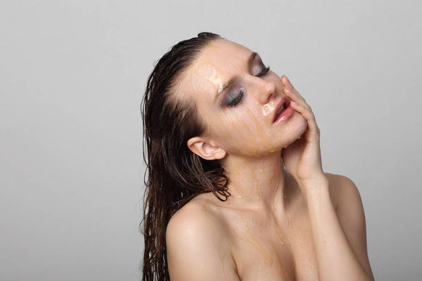 Beautiful woman with honey on her face - Photo, Image