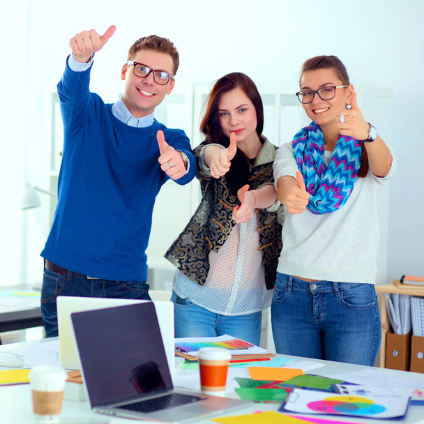 Young business people standing at office near desk and showing ok - Zdjęcie, obraz