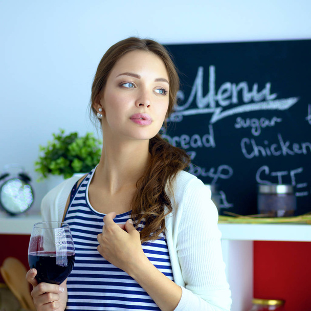 Csinos nő iszik egy kis bort otthon a konyhában. . - Fotó, kép