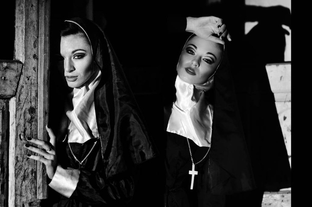 zwei schöne sexy Nonnen in einer dunklen mystischen, geheimnisvollen Kirche, die nachts besetzt ist. Schwarz-Weiß-Foto von zwei ähnlichen nuns.nun Zwillingen auf schwarzem Hintergrund. Nonnenkostüm zu Halloween. zwei verführerische Nonnen allein - Foto, Bild