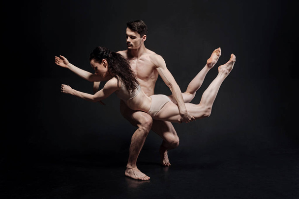 Powerful young athletes performing in front of the black wall - 写真・画像