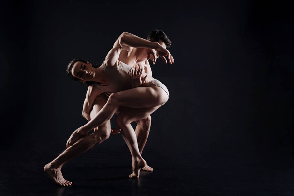 Flexible gymnasts performing in the black colored studio - Фото, изображение