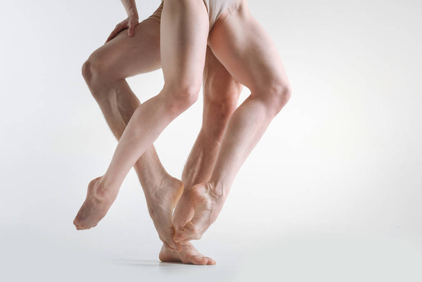 Muscular athletes legs dancing in the white colored studio - Foto, Imagem
