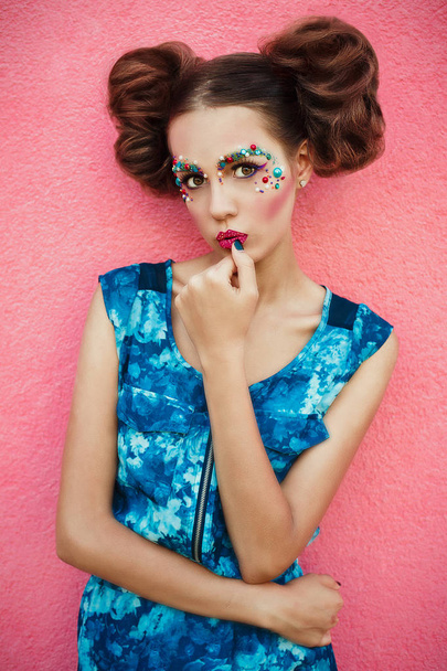 Imagem elegante do modelo na moda com dois coque de cabelo e maquiagem profissional criativa posando no fundo rosa. Maquiagem criativa e penteado
. - Foto, Imagem