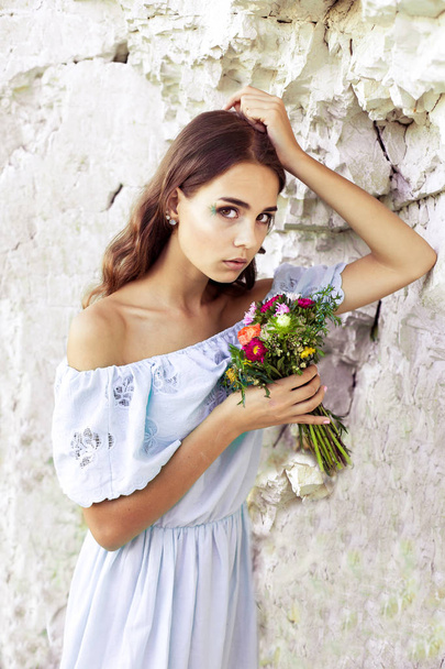 Portrait of pretty beautiful girl holding flowers. Picture of cute girl with bouquet of flowers in summertime. - Foto, Imagem