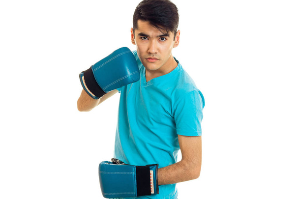 young angry brunette man in blue boxing gloves practicing isolated on white background - Foto, Bild