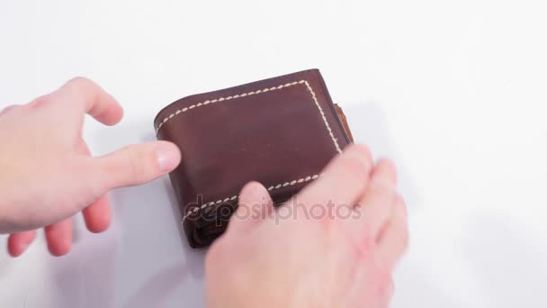 Hnědá peněženka na bílém pozadí. Muž líčí peníze z rozpočtu a bere vše. Detailní záběr - Záběry, video