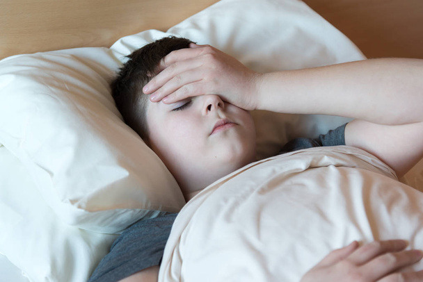 boy with headache lying in bed - Fotó, kép