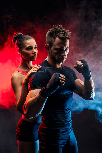 Strong boxer in stance with handwraps on his fists. With girlfriend standing behind him. - Фото, зображення