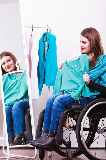handicapped girl on wheelchair choosing clothes - Foto, imagen