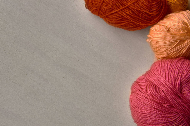 Rose, red and orange balls of yarn on white wooden background. - Foto, Imagen