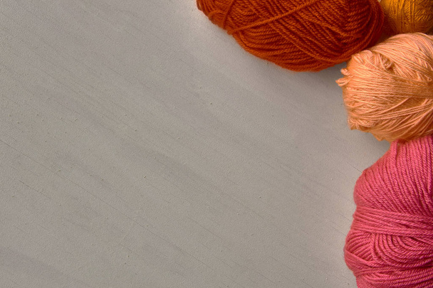 Rose, red and orange balls of yarn on white wooden background. - Foto, Imagen