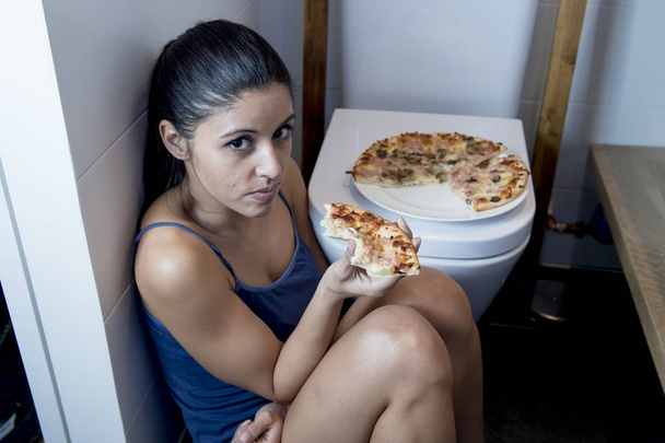 過食症の女性気分が悪く有罪ピザを食べてトイレにトイレの床に座って - 写真・画像
