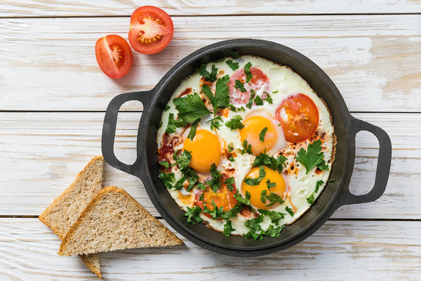 Pan of fried eggs, tomatoes and parsley with bread - Φωτογραφία, εικόνα