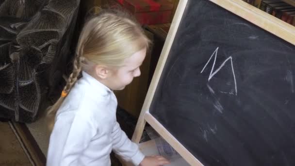 Little girl draws chalk on blackboard - Felvétel, videó