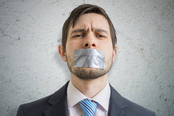 Censorship concept. Young man is silenced with duct tape over his mouth. - Photo, Image