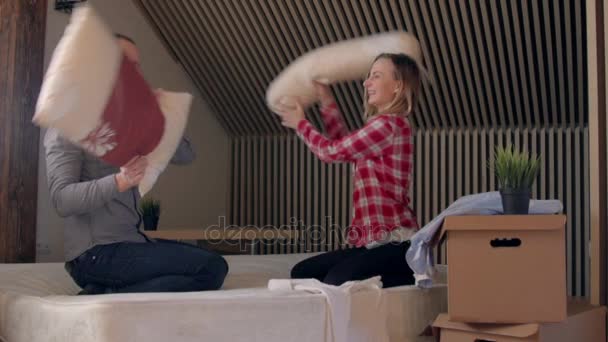 Young couple having a pillow fight in a home bedroom - Imágenes, Vídeo