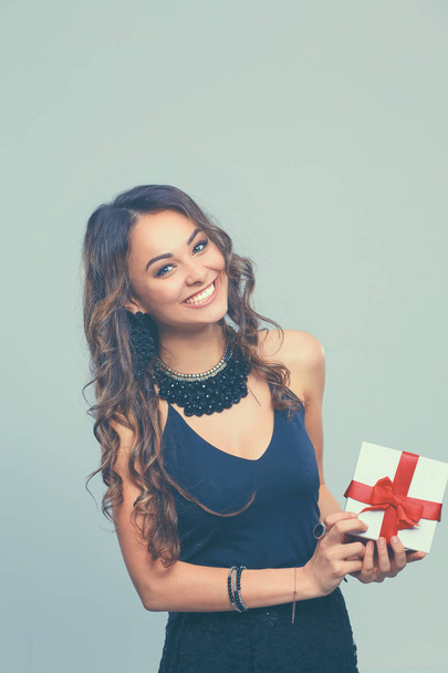 Young woman happy smile hold gift box in hands, isolated over gray background - Fotografie, Obrázek