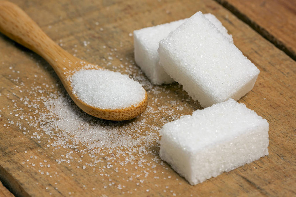 sokerikuutio lusikassa puupohjalla
 - Valokuva, kuva