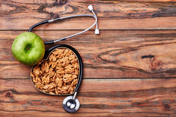 Green apple, walnuts and stethoscope. - Φωτογραφία, εικόνα