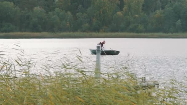 Łódź wiosłowa pielęgniarka na jezioro, człowiek w polecenia net włosów do megafon - Materiał filmowy, wideo