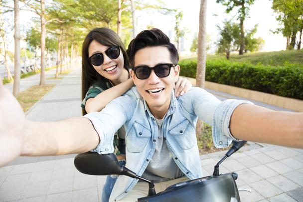 счастливая молодая пара катается на скутере и делает селфи
 - Фото, изображение