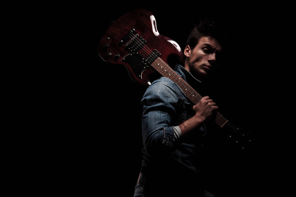 side view of a guitarist holding his guitar on shoulder  - Photo, Image