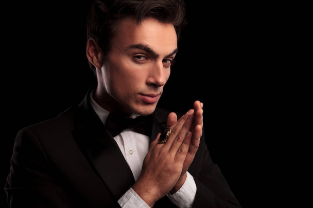 elegant man in tuxedo wearing big ring rubbing his palms - Foto, afbeelding