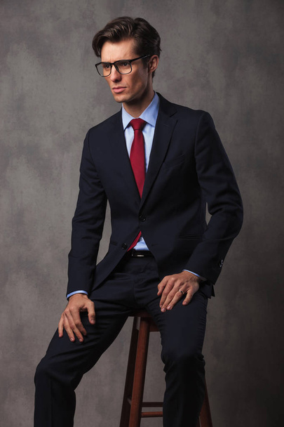 сидячий бізнесмен в окулярах і руках на колінах
 - Фото, зображення
