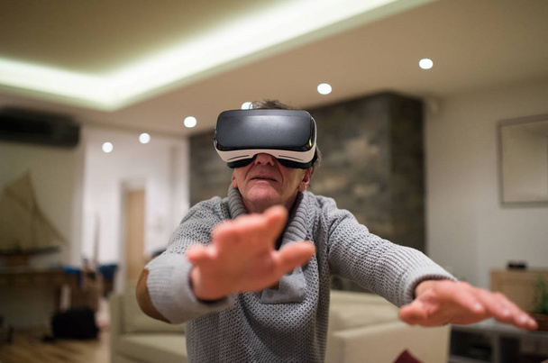Senior man wearing virtual reality goggles at home - 写真・画像