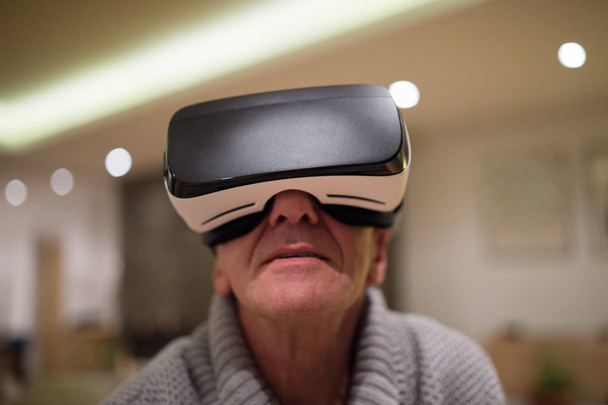 Senior man wearing virtual reality goggles at home - 写真・画像