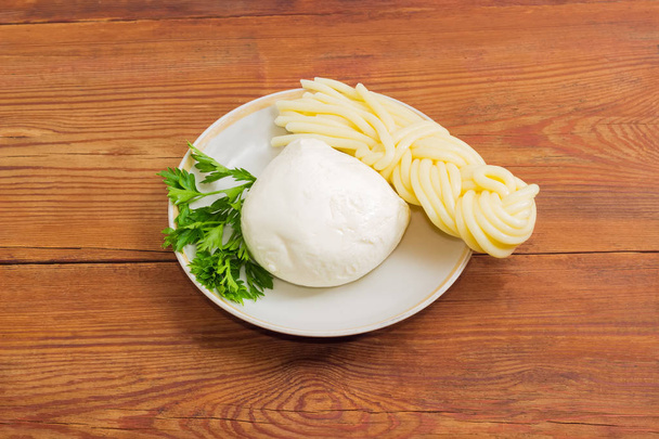 Kahdenlaisia mozzarella juustoa ja persiljaa lautasella
 - Valokuva, kuva