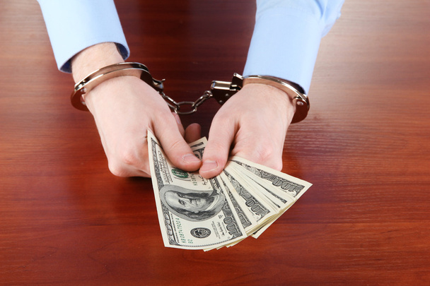 Businessman in handcuffs counts the money for bribes - Фото, изображение