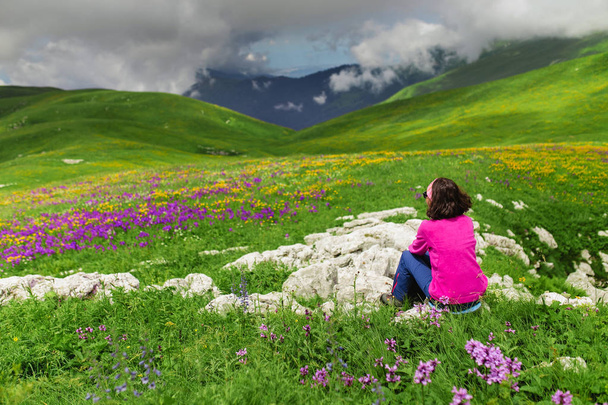 Hermosa mujer sentada en la cima de la montaña y mirando el paisaje
 - Foto, imagen
