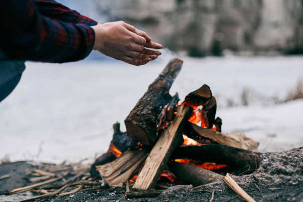 Girl warms hands near a fire in winter - Zdjęcie, obraz