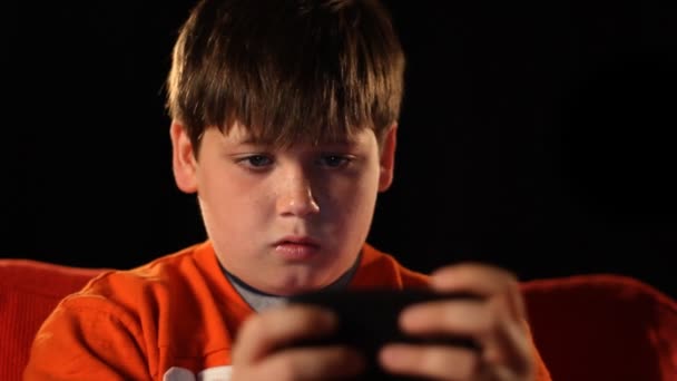 młody chłopak gra przenośnych gier wideo w ciemności. - Materiał filmowy, wideo