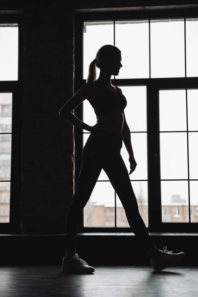 Silhouette of woman athlete standing near the window - Fotoğraf, Görsel