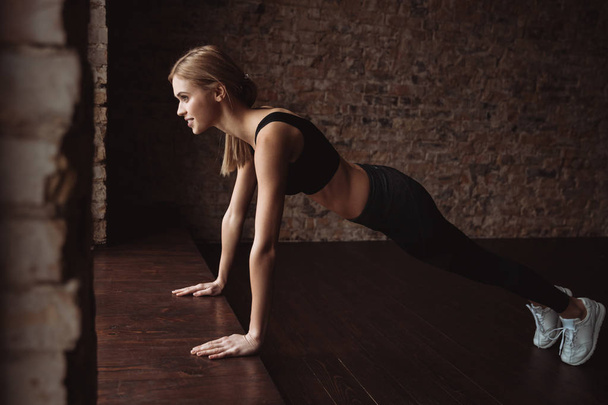 Happy attractive young sportswoman doing pushups - Photo, Image