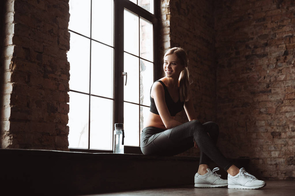 Beautiful young fitness lady sitting in gym - Fotoğraf, Görsel