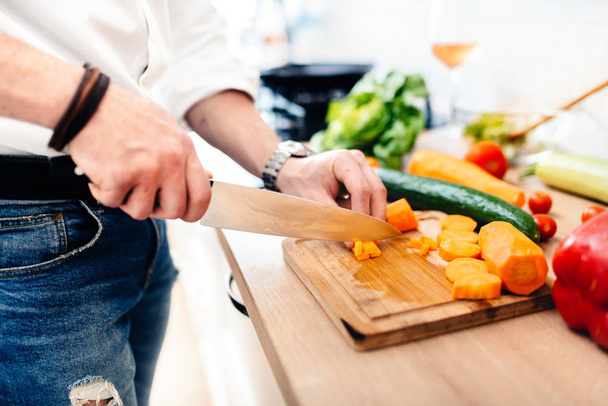 close up of kitchen chef, master cook preparing dinner. details of knife cutting vegetables in modern kitchen - Fotó, kép