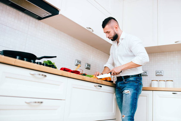 Handsome man cooking. Details of modern cook with knife and kitchen dish - Valokuva, kuva