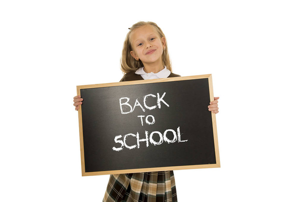 школьница улыбается счастливо держа и показывая маленькую доску с текстом обратно в школу
 - Фото, изображение