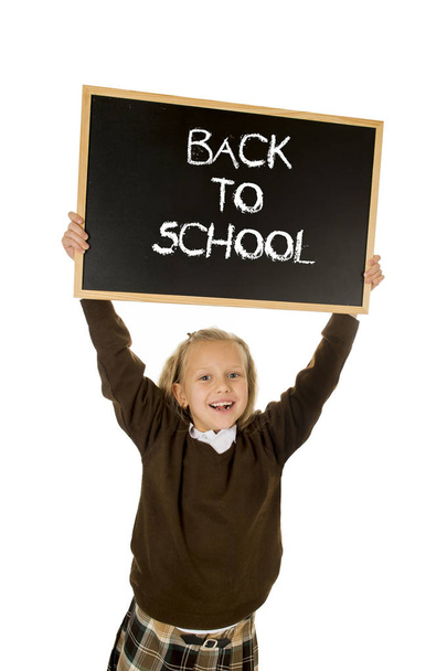 schoolgirl smiling happy holding and showing small blackboard with text back to school - Foto, imagen