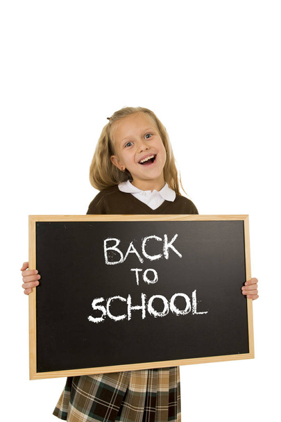 schoolgirl smiling happy holding and showing small blackboard with text back to school - Фото, изображение