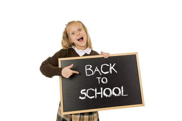 schoolgirl smiling happy holding and showing small blackboard with text back to school - Фото, зображення