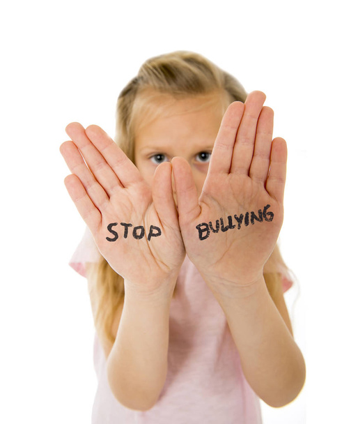 γλυκό και φοβισμένος μικρή μαθήτρια δείχνει εκφοβισμού στάση το κείμενο γραμμένο στα χέρια της - Φωτογραφία, εικόνα