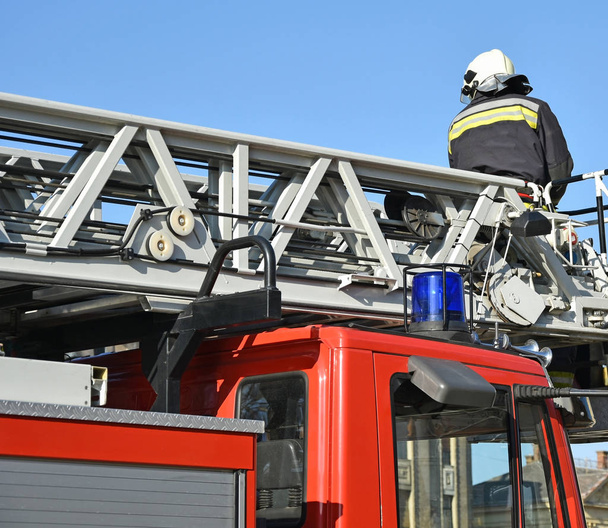 Feuerwehrmann arbeitet auf dem Dach eines Feuerwehrfahrzeugs - Foto, Bild