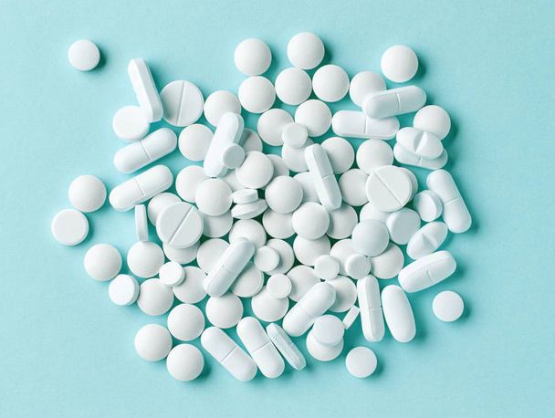 varias píldoras blancas sobre fondo azul
 - Foto, Imagen